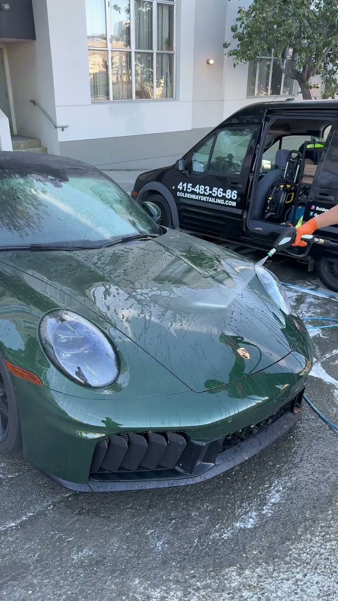 A ceramic-coated Porsche 911 GTS being rinsed down beside the Golden Bay Detailing van