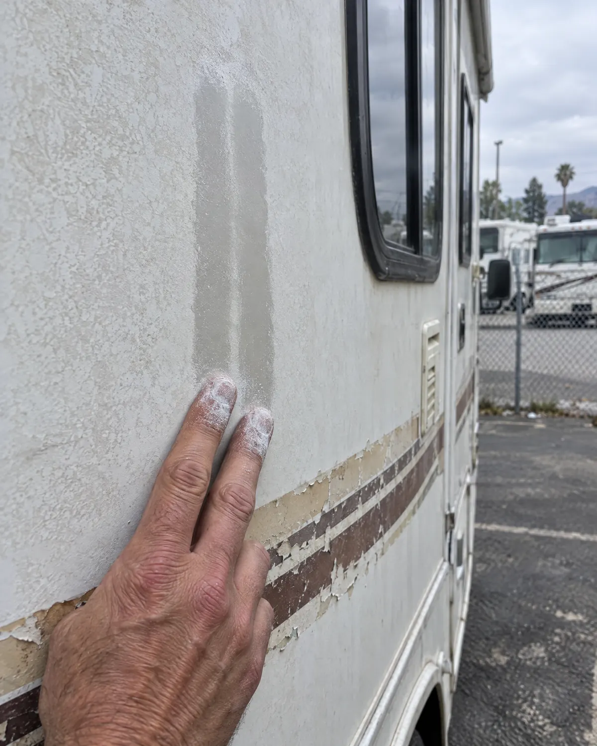Illustration: fingertips covered in white chalk after wiping an oxidized RV sidewall