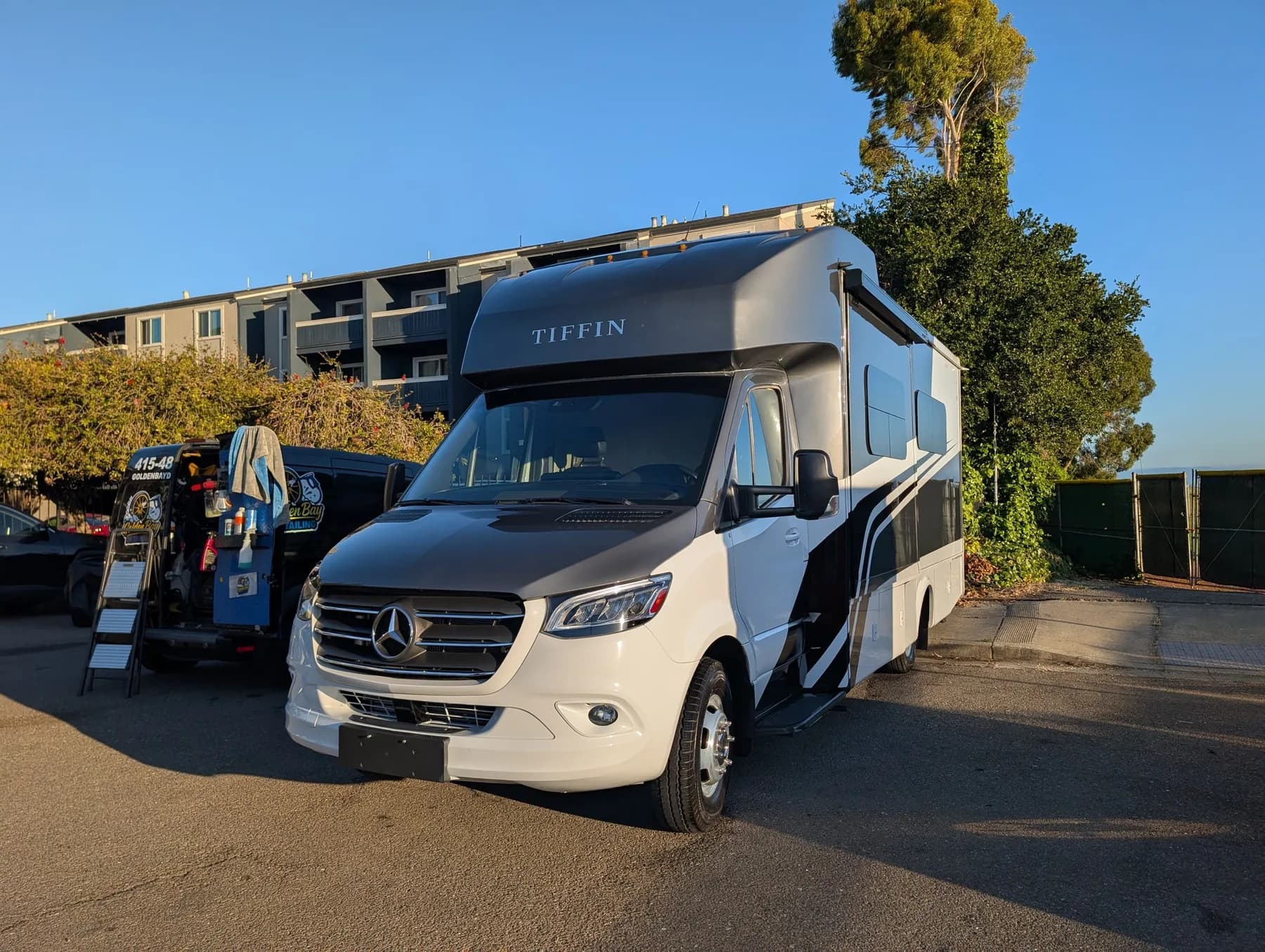 Tiffin Wayfarer motorhome gleaming at golden hour after a Golden Bay exterior detail, the Golden Bay van parked beside it