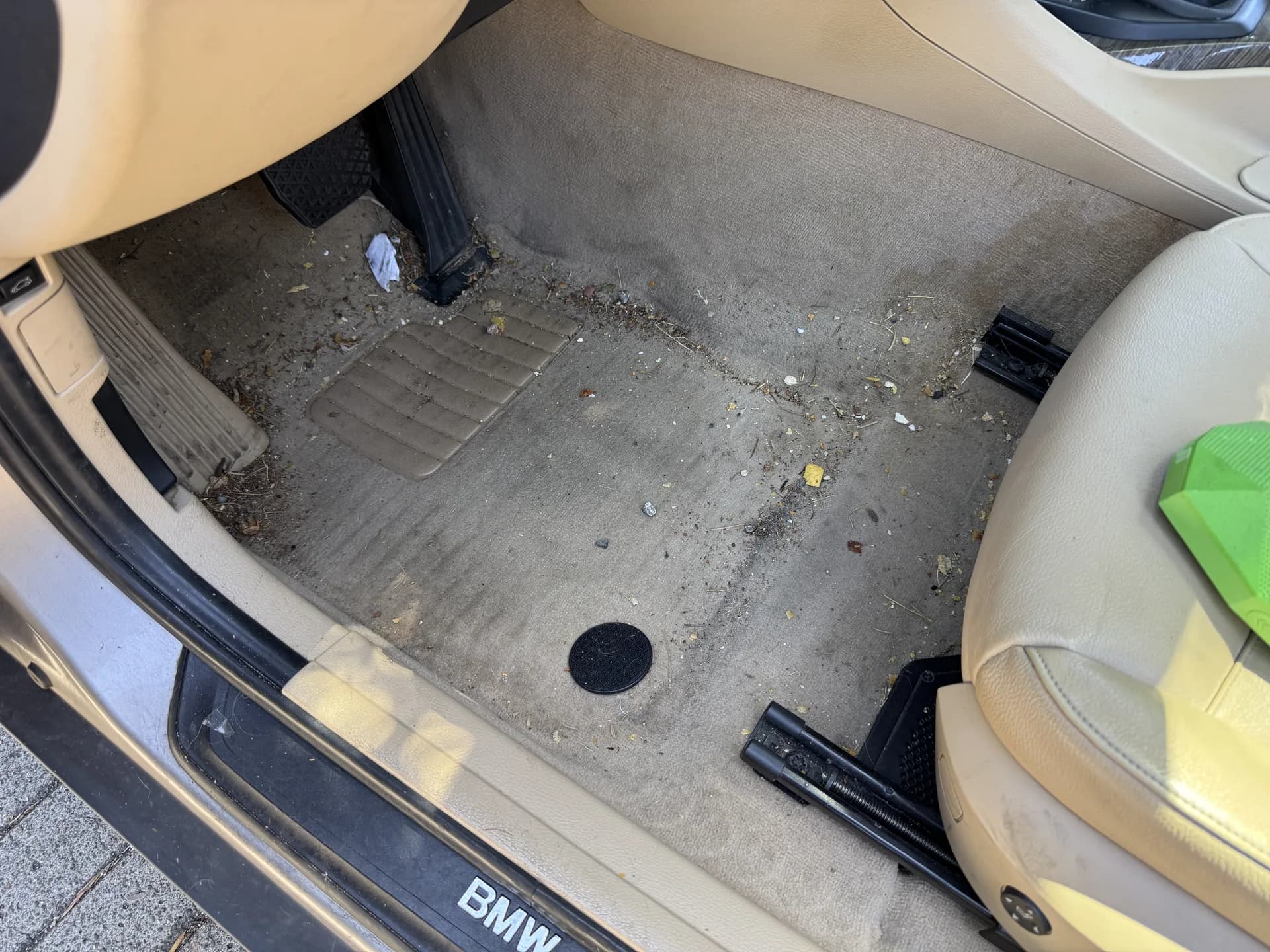 BMW 3-Series footwell carpet soiled with dirt and debris before detailing