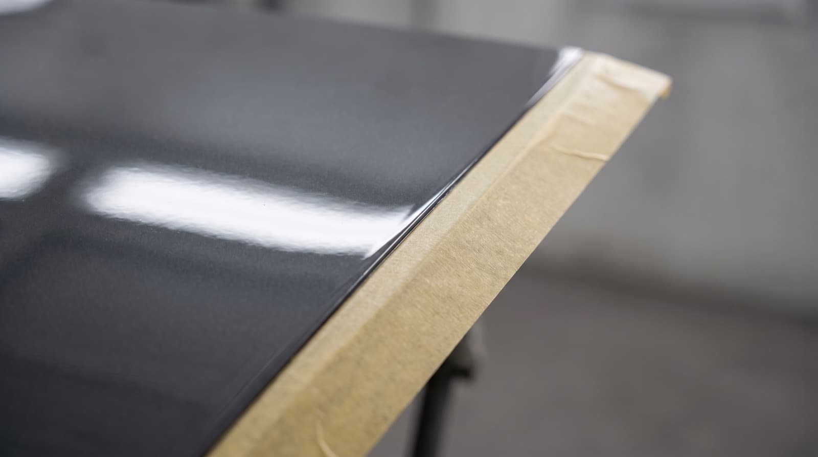 Close-up of water beading on the glossy hood of a black car after a clear coating was put on the paint.