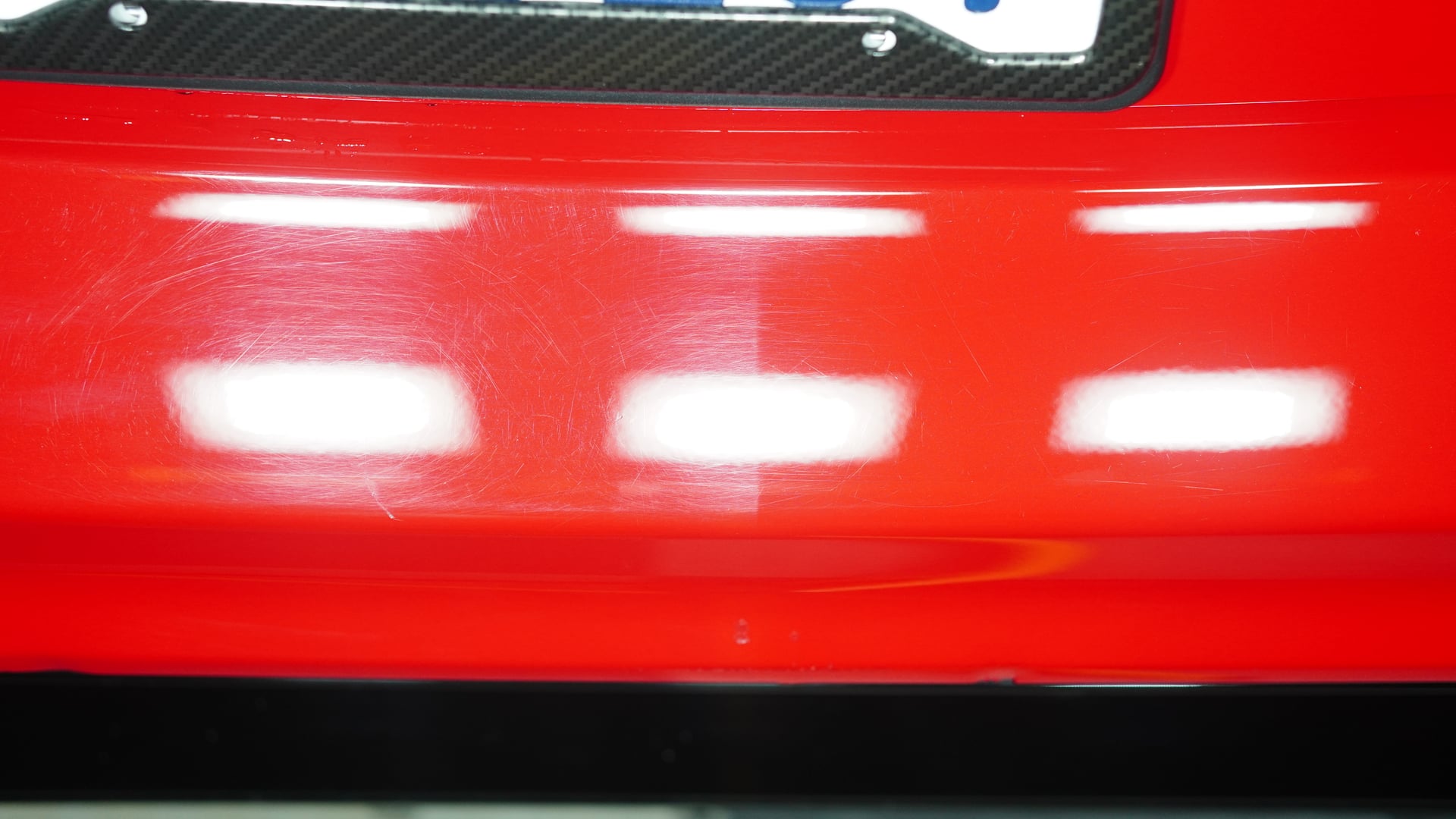 50/50 paint correction demonstration on a red bumper in San Francisco — one half covered in swirl marks and fine scratches, the other half machine-polished to a mirror finish by Golden Bay Detailing